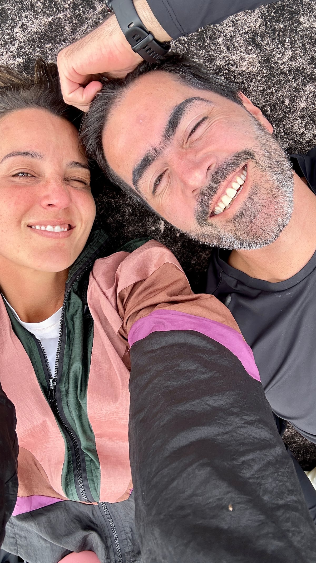 Thaíssa e Julián de rosto colado, cansados e rindo, no meio da trilha